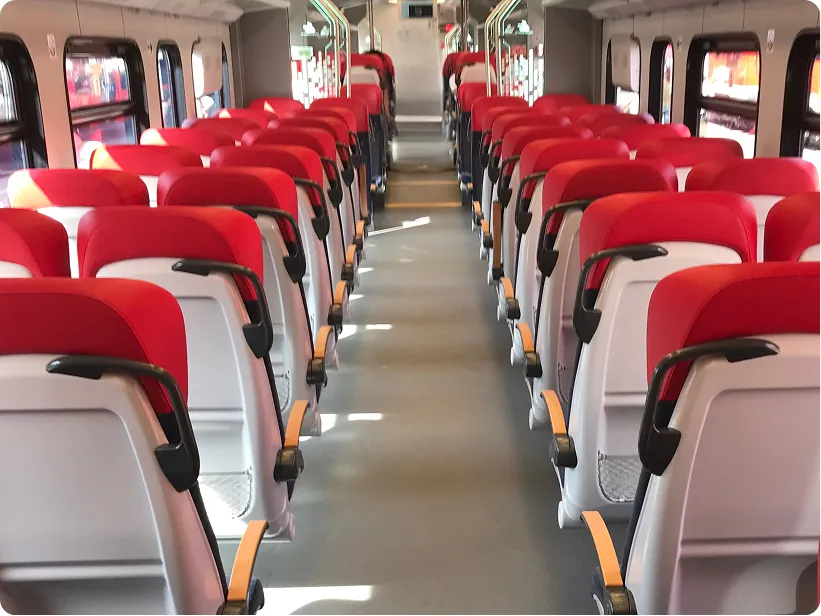 Rows of red seats along the aisle of a regional train