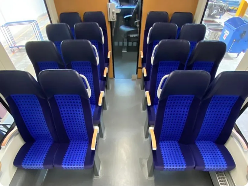 Rows of blue seats seen from the aisle of a regional train